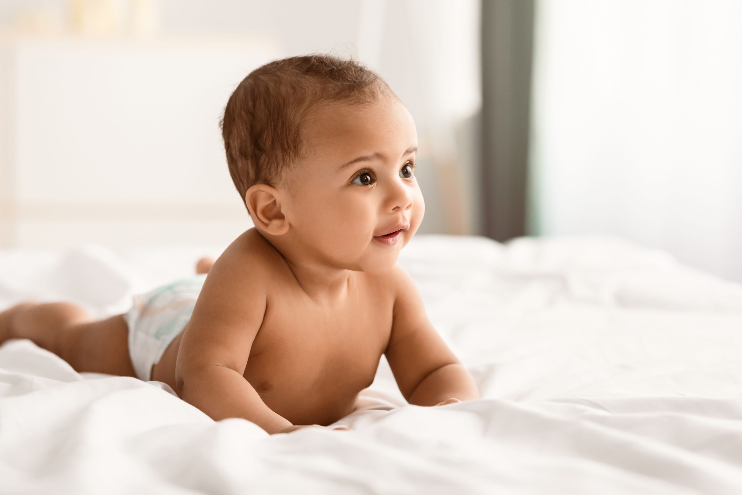 Curious adorable little infant lying on bed