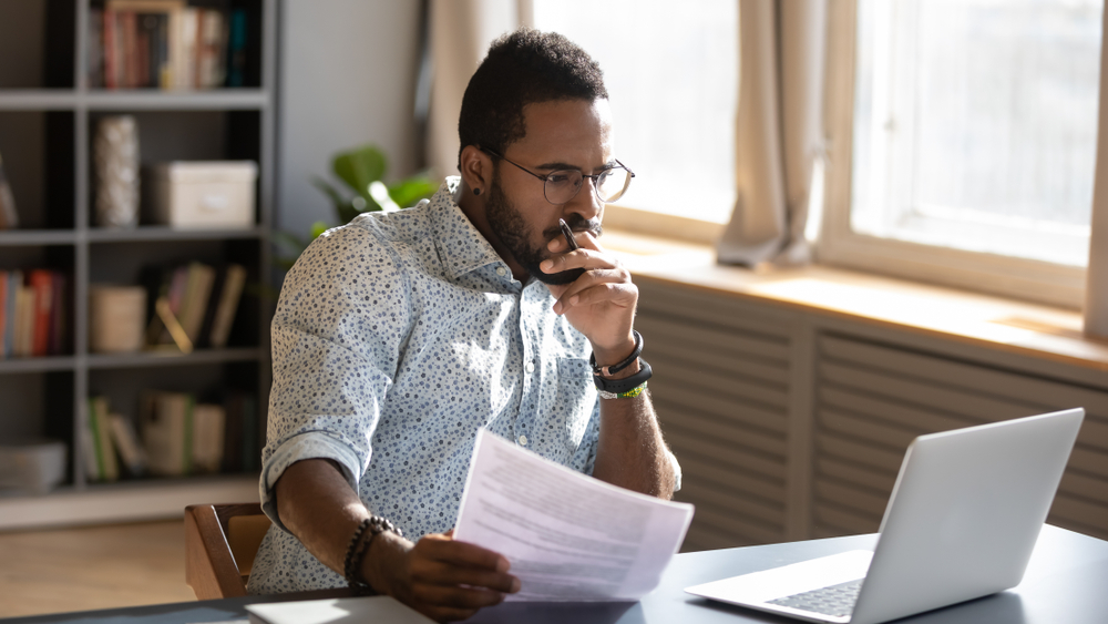 man looking at laptop and forms