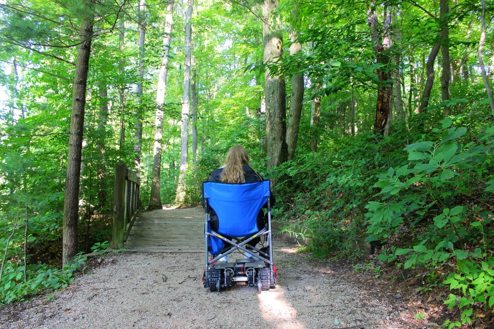 Photo of woman in a WheelTrax wheelchair on a trail at Hemlock Crossing Park